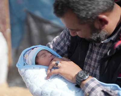 A father looks over his little baby which is wrapped in a baby blanket.